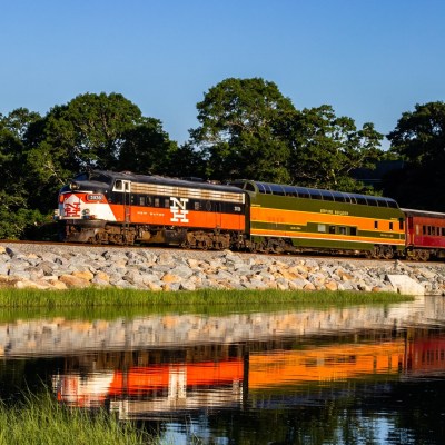 a large long train on a track next to some water