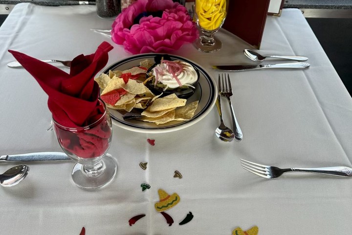 Table with menus, flower petals, chips, and folded napkins on a train.