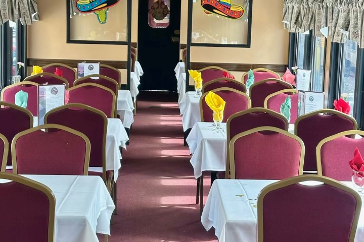 Train dining car with pink seats, white tablecloths, and sombrero decorations.
