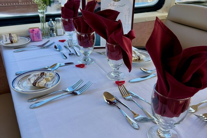 Elegant table setting with red napkins, a rose, and a window view of snowy landscape.